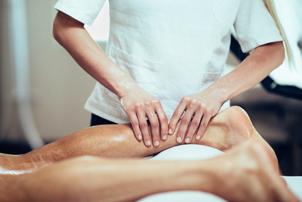 Sports Massage - Massage therapist working with patient, massaging his calves. Toned image.